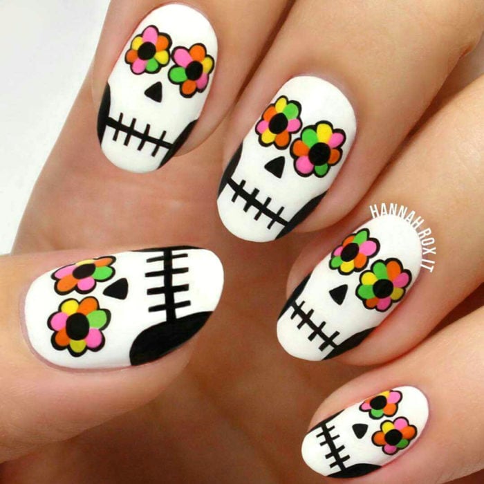 Manicura de Día de Muertos; uñas en forma de almendra pintadas con calaveras de dulce con ojos de flores de altar