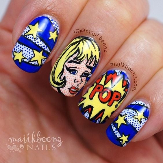 Manos de una chica con diseño de uñas pop art en color azul con viñetas de cómics 