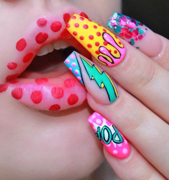 Manos de una chica con diseño de uñas pop art en colores amarillo, rosa y azul 