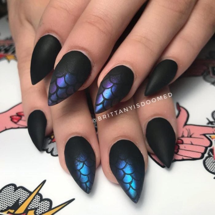 Chica con las uñas pintadas de color negro con tonos tornasol azules con telarañas 