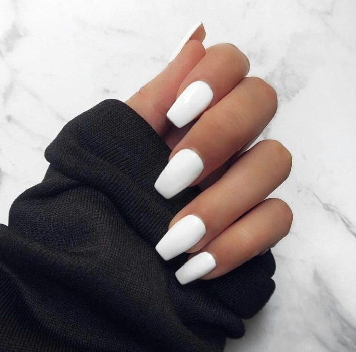 Chica mostrando sus uñas de color blanco