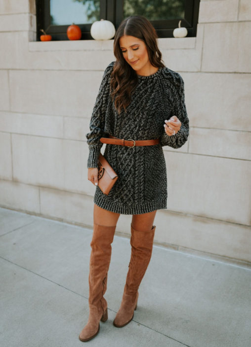 Chica de cabello castaño con vestido gris tejido, con cinto y botas de gamuza café largas arriba de la rodilla 