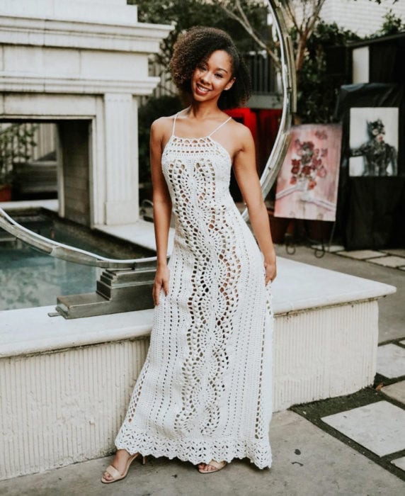 Mujer afroamericana con cabello chino y vestido tejido blanco y largo