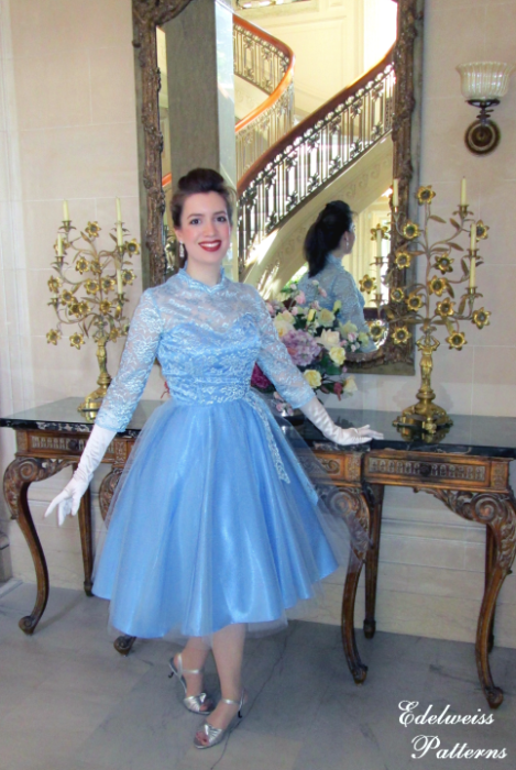 Katrina Holte con un vestido azul cielo estilo vintage frente a un espejo y una mesita vintage