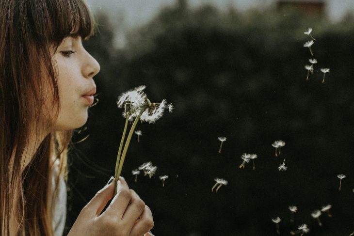 Mujer soplándole a una flor