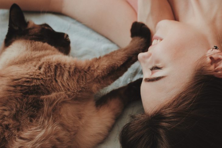 Mujer y gatito acostados en la cama