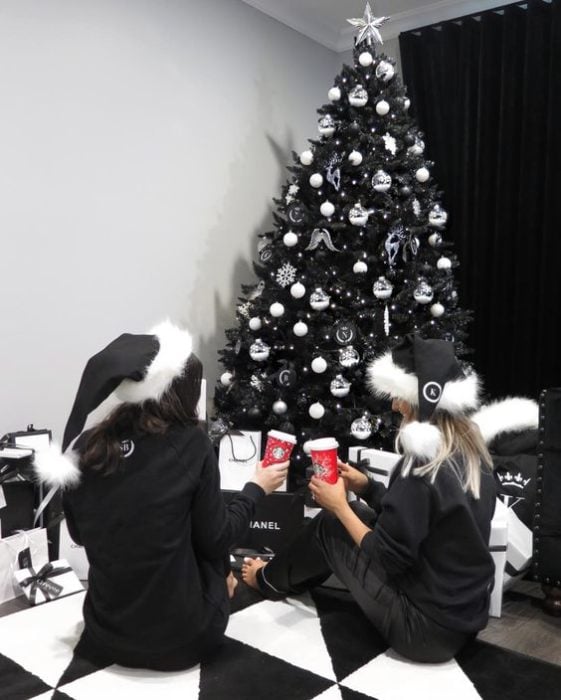 Chicas sentadas al pie del pino navideño en color negro