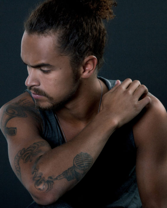 Finlandia te paga por tener bebés; guapo chico finlandés de cabello chino y largo agarrado en una cola de caballo, con tatuajes en los brazos