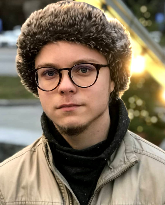 Finlandia te paga por tener bebés; guapo chico finlandés de ojos grises, con lentes y gorro peludo