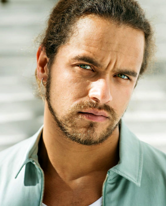 Finlandia te paga por tener bebés; guapo chico finlandés de ojos verdes, cabello chino y largo peinado con una coleta, hombre serio con barba de candado