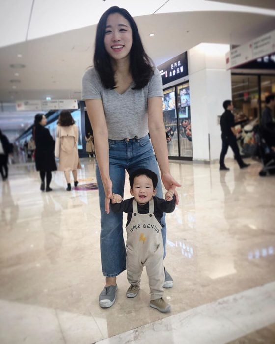 Mamá ayudando a su hijo a caminar mientras están en un centro comercial 