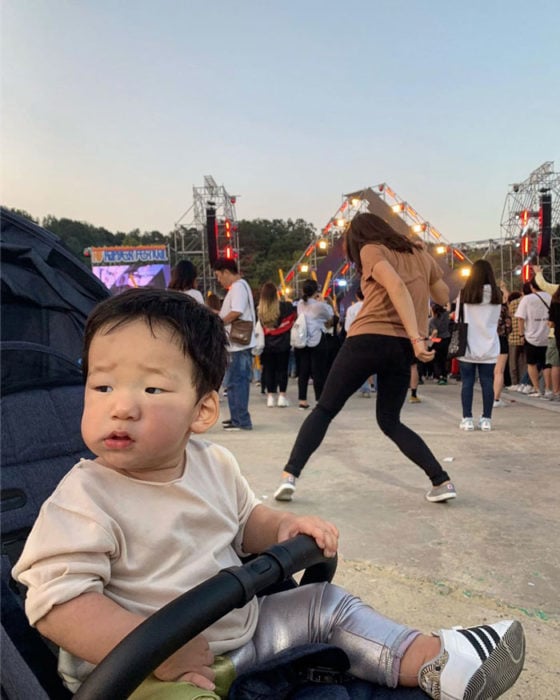 Mamá bailando en un festival mientras su hijo la observa desde la carreola 