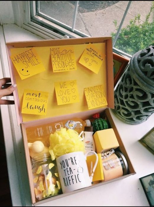 Caja de regalo rellena con una taza y post-it amarillos