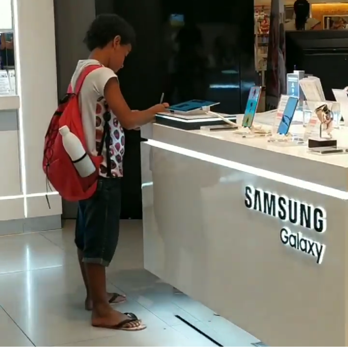 Niño hace tarea en una tienda de celulares porque no tiene Tablet