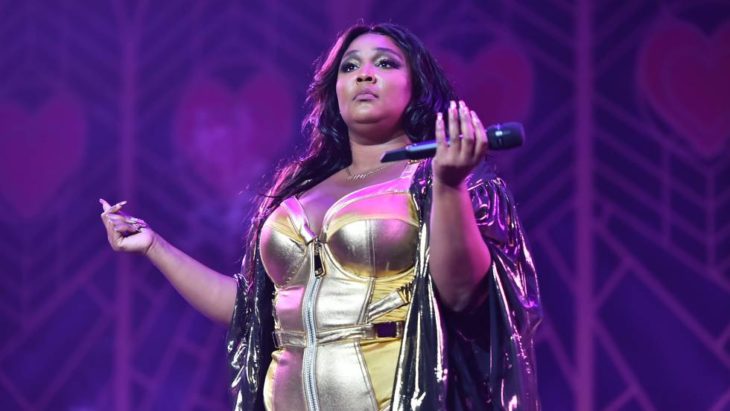 Cantante Lizzo en uno de sus conciertos usando un vestido de color dorado 