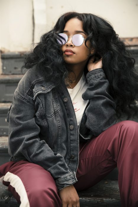 Cantante H.E.R sentada en unas escaleras y posando para una foto 