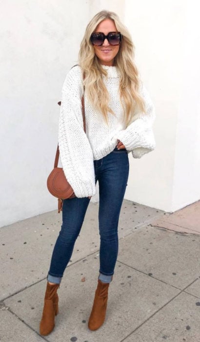 Chica usando unos jeans de color azul, suéter de color blanco y botines color camel 