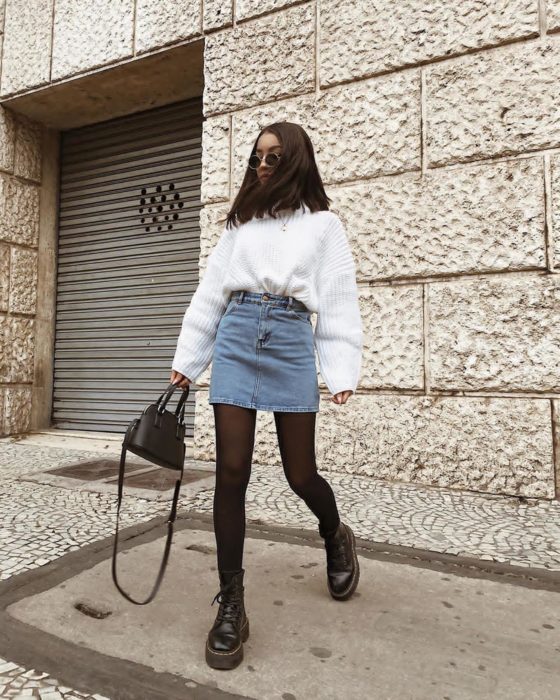 Chica usando una falda de mezclilla con un suéter grande y abrigador de color blanco 