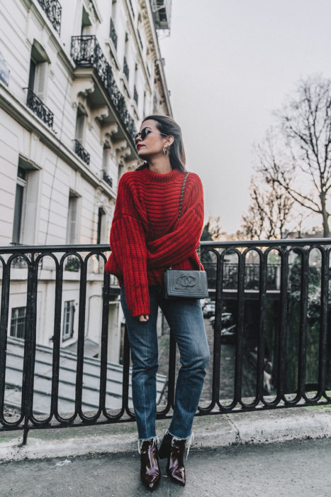 Chica usando un sueter de color rojo con jeans y botines de charol en color vino 