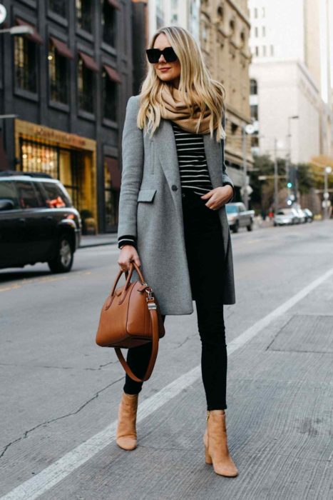 Chica usando un abrigo de color azul con jeans y blusa de color negro con botines camel 