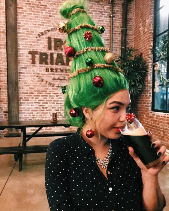 Chica llevando un peinado alto con cabello en verde y esferas en rojo 