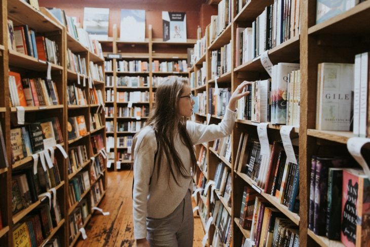 Chica buscando libros en una biblioteca