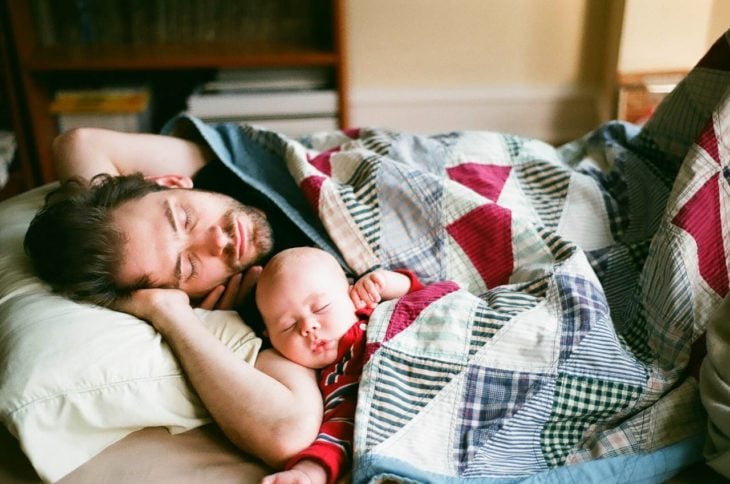 Hombre durmiendo junto a un bebé sobrino