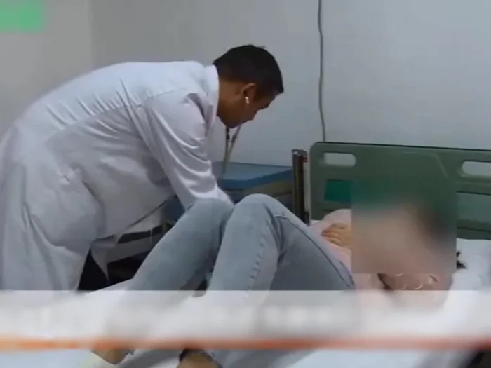 Mujer recostada en una camilla siendo revisada por un doctor 