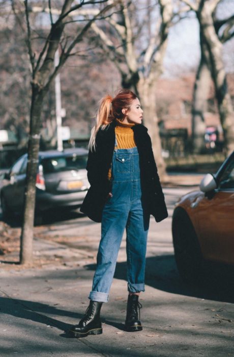 Chica usando un overol con un bluson amarillo y saco de color negro 