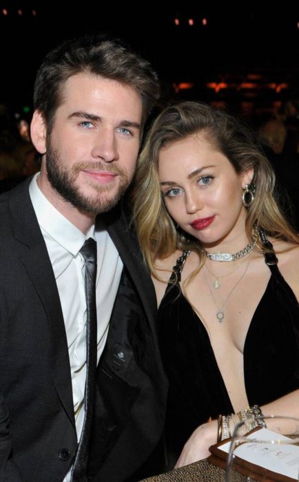 Miley Cyrus y Liam Hemsworth posando para una foto mientras están sentados en una cena 