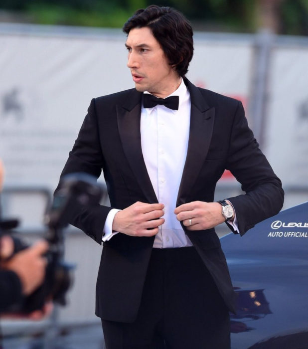 Actor Adam Driver; hombre de cabello oscuro y largo, abrochándose el saco de vestir