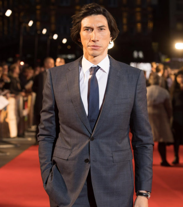 Actor Adam Driver en la alfombra roja; hombre con traje gris, corbata azul, cabello largo