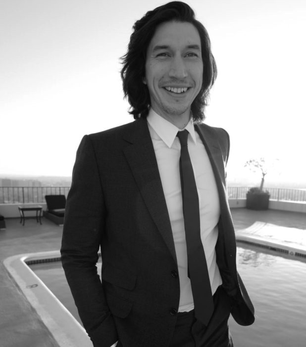 Actor Adam Driver; hombre con traje, saco y corbata, de cabello negro, largo y lacio, sonriendo 