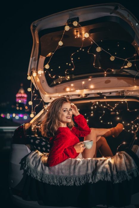 Ragazza dentro un'auto piena di luci nel bagagliaio