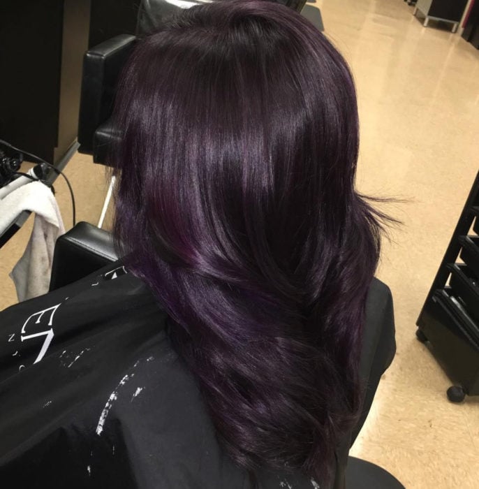 Chica mostrando su cabello de color dark violeta después de que se lo tiñeron 