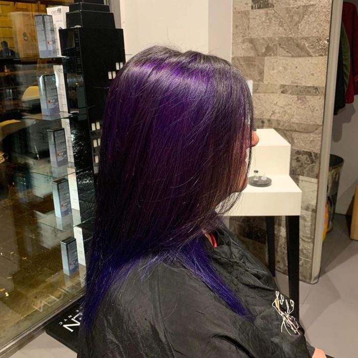 Chica mostrando su cabello de color dark violeta después de que se lo tiñeron 