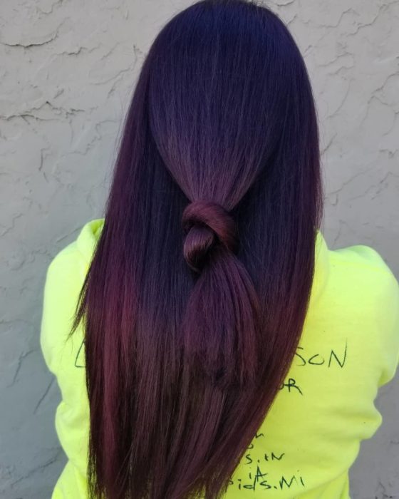 Chica mostrando su cabello de color dark violeta sujetado en una coleta 