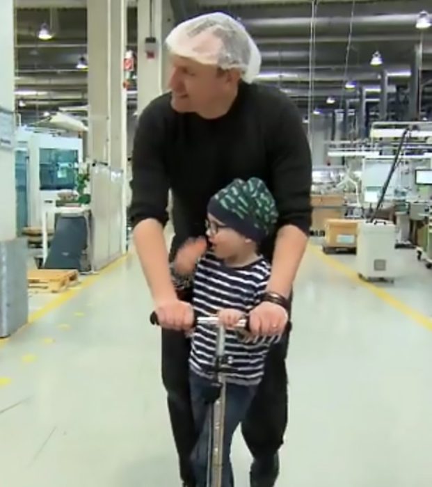 Padre e hijo jugando en un patín dentro de una fabrica 