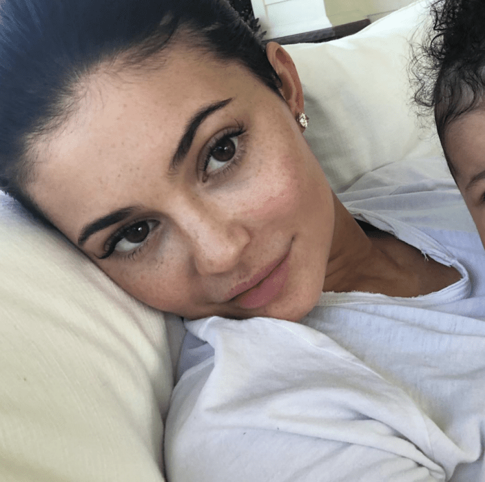 Kylie Jenner sin maquillaje, recostada en su cama 