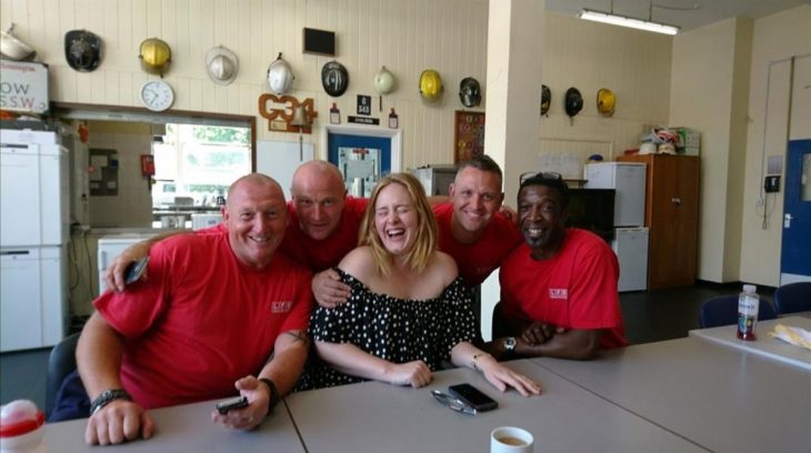 Adele junto a un grupo de bomberos sonriendo