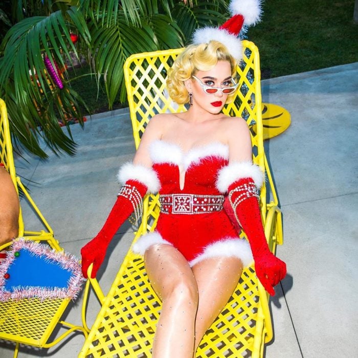 Katy Perry vestida como Santa Claus mientras está sentada en una silla de alberca 