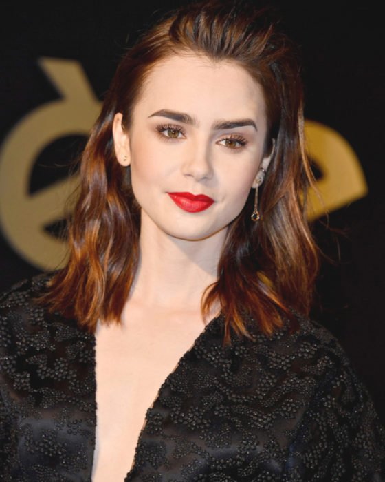 Peinados de Lily Collins para Año Nuevo; mujer de cabello castaño rojizo con efecto mojado, maquillaje natural