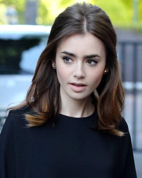 Peinados de Lily Collins para Año Nuevo; mujer de cabello castaño, lacio peinado en media cola estilo Adele