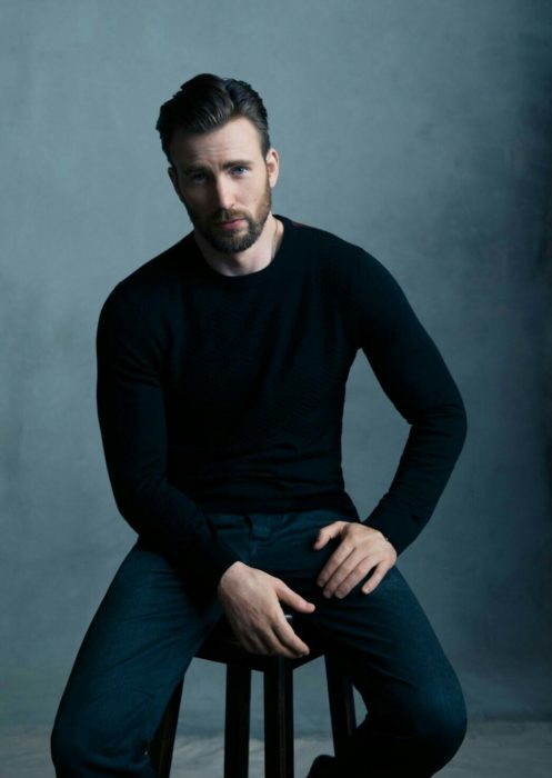 Chris Evans sentado en un banco posando para una foto