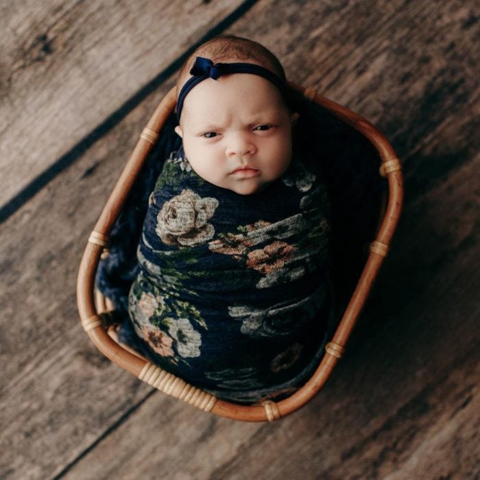 Bebé recostada en una canastilla durante una sesión de fotos con el rostro de molestia 