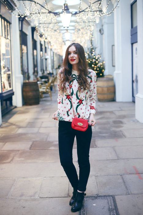 Chica usando un feo suéter navideño con unos jeans y botines 