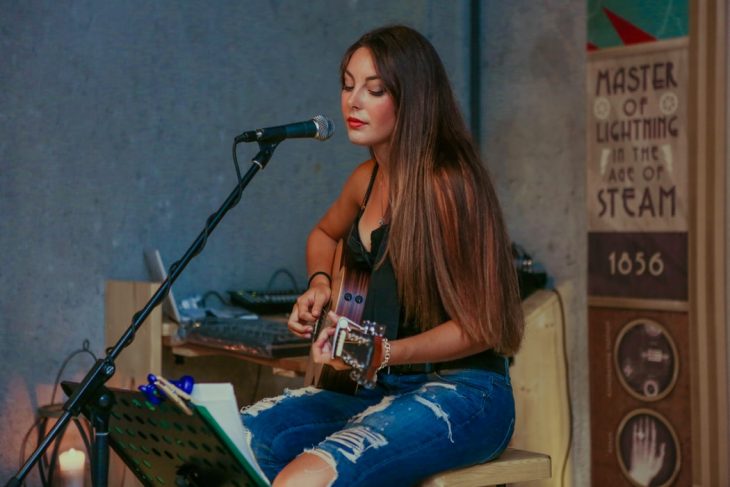 Chica tocando la guitarra y cantando acapela 