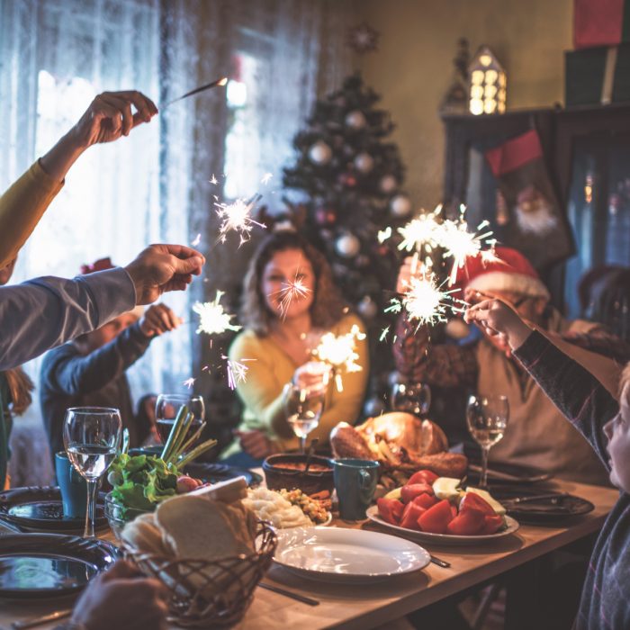 Familia reunida en cena de Navidad, con luces de bengala 