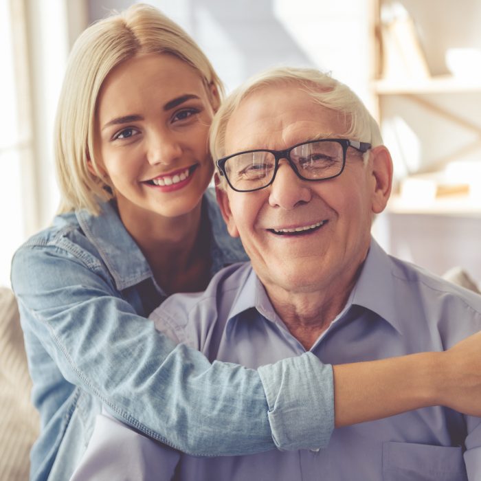 Abuelo y nieta abrazados y sonriendo 