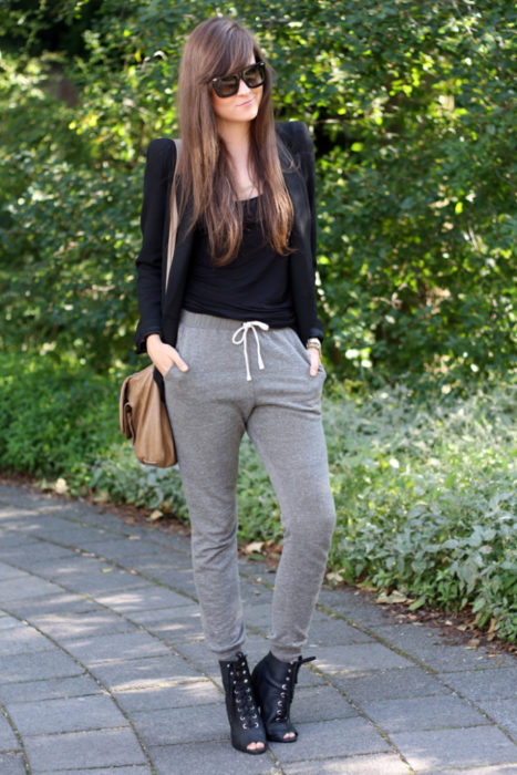 Chica usando unos pants de color gris con una blusa de color negro y zapatos de cintas 
